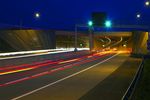Foto: hell erleuchteter, mehrspuriger Straßentunnel bei Nacht; fotografiert mit dynamischer Bewegungsunschärfe der Fahrzeuglichter